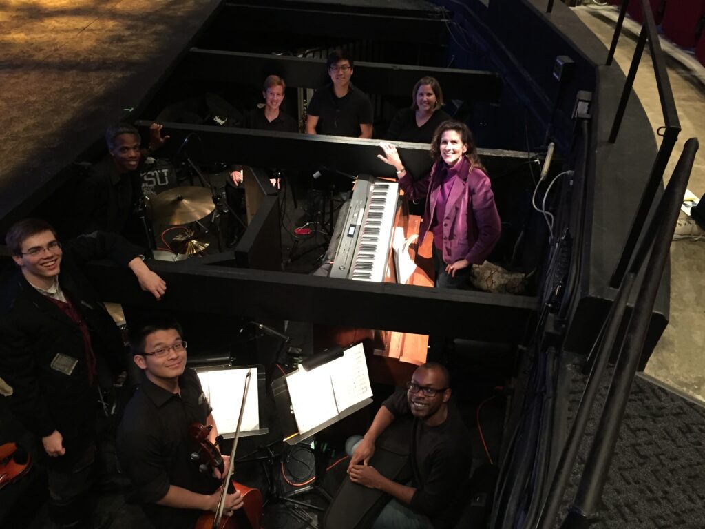 A group of people standing around a piano